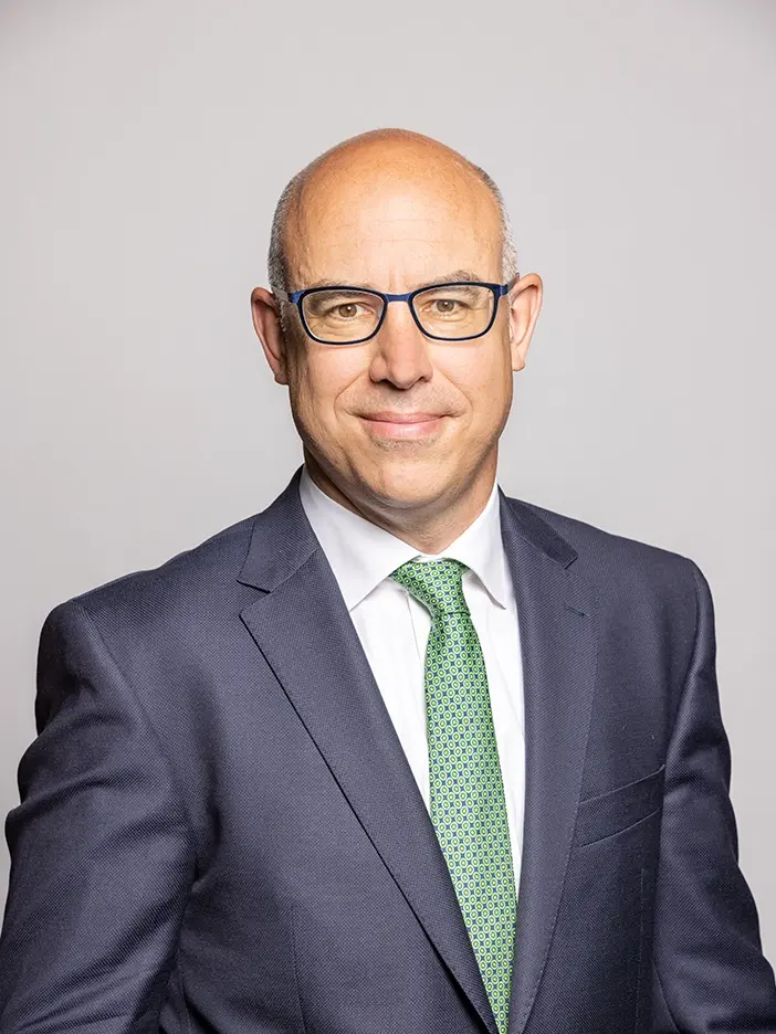 Gabriell Felbermayr blickt lächelnd in die Kamera. Er trägt eine blaue dezente Brille und hat braune Sein Anzug ist ebenfalls dunkelblau die Krawatte ist grün-weiß gemustert.