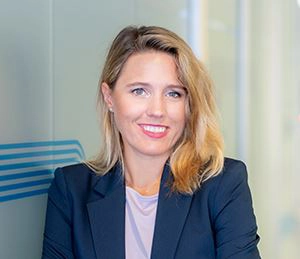 Tanja Spennlingwimmer trägt ein fliederfarbenes T-Shirt, einen dunkelblauen Blazer, blonde Haare und ein Lächeln.