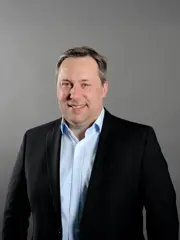 Marian Rappl hat graumeliertes Haar und blaue Augen. Er trägt ein hellblaues Hemd und ein schwarzes Sakko.
